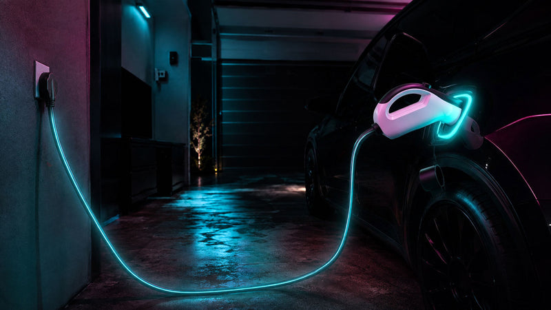 WenStorm Level 2 Portable EV Charger with handle-integrated electronics plugged into a NEMA 14-50 garage outlet, EV charging overnight in the background.